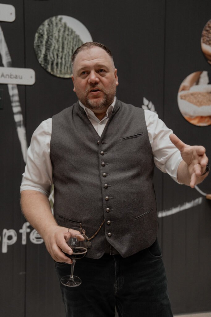 Matthias Willig mit Bierglas vor dunkler Wand
